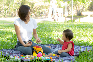 Beautiful young asian mom and daughter playing toy blocks for learning development happy and fun at park in summer, mother and kid cheerful activity together at garden in holiday, family concept.