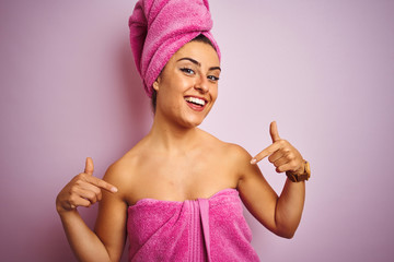 Young beautiful woman wearing towel after shower over isolated pink background looking confident with smile on face, pointing oneself with fingers proud and happy.