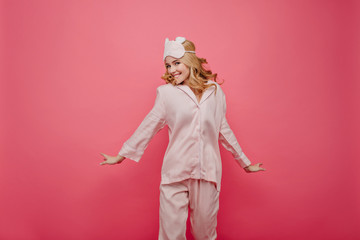 Caucasian carefree girl in silk nightwear enjoying good day. Chilling fair-haired woman in silk pajama jumping and laughing.