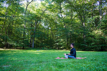 Young male meditating in beautiful outdoor park
