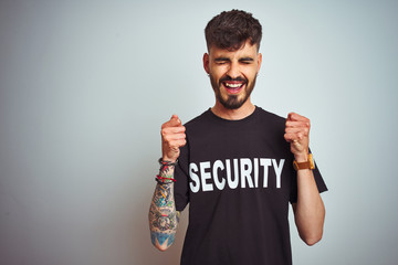 Young safeguard man with tattoo wering security uniform over isolated white background excited for...