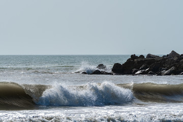 Beach view with waves and a rocky outpoint in Florida