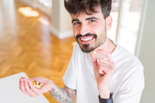 Young man eating hazelnuts, close up of hand with a bunch of healthy nuts