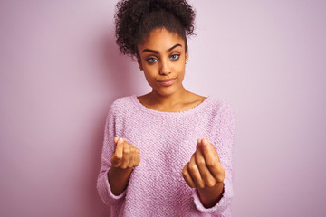 Young african american woman wearing winter sweater standing over isolated pink background doing...