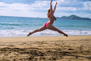 Fototapeta na wymiar young woman jumping on the beach