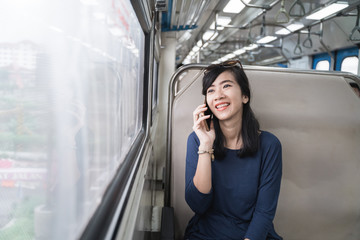 Fototapeta na wymiar portrait of asian woman enjoying train trip or tram with her mobile phone