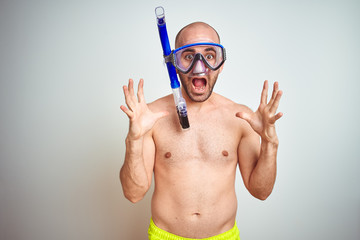 Young man wearing diving snorkel goggles equipent over isolated background celebrating crazy and amazed for success with arms raised and open eyes screaming excited. Winner concept