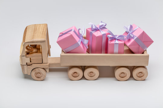 Toy wooden car with gifts. Elegant boxes with gifts in back of truck. Copy space, holiday concept. Discounts, sale.