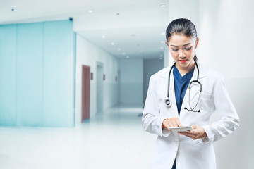 Asian woman doctor in white lab coat and stethoscope using tablet