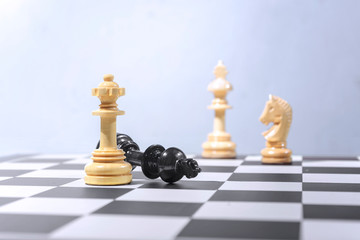 Black king chess piece defeated by wooden queen chess piece