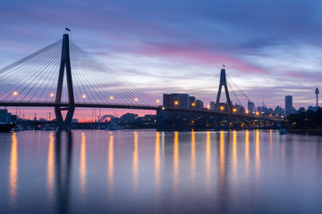 Dawn at Anzac Bridge, Sydney Australia. Bridge lights reflecting across Sydney Harbour before sunrise. Photo taken Blackwattle Bay park in Glebe.