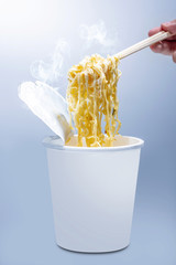 People eat the instant cup noodles with chopstick