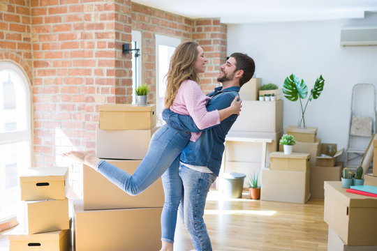 Young beautiful couple in love celebrating moving to a new home around cardboard boxes