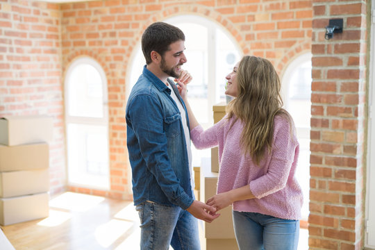 Young couple dancing celebrating moving to new apartment around cardboard boxes