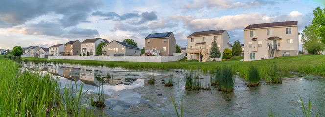 Fototapeta na wymiar Beautiful multi storey homes built in front of a grassy and shiny pond