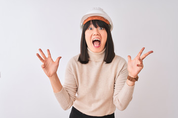 Obraz na płótnie Canvas Young beautiful Chinese architect woman wearing helmet over isolated white background celebrating crazy and amazed for success with arms raised and open eyes screaming excited. Winner concept