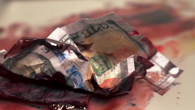 Blood Money dirty with fly buzzing around slowly moving close up one hundred dollar bills cash isolated with shallow depth of field