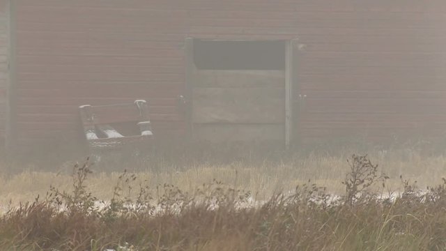 Close up of red barn door on eerie foggy day.