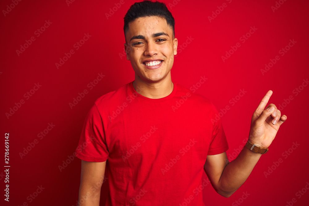 Wall mural young brazilian man wearing t-shirt standing over isolated red background with a big smile on face, 