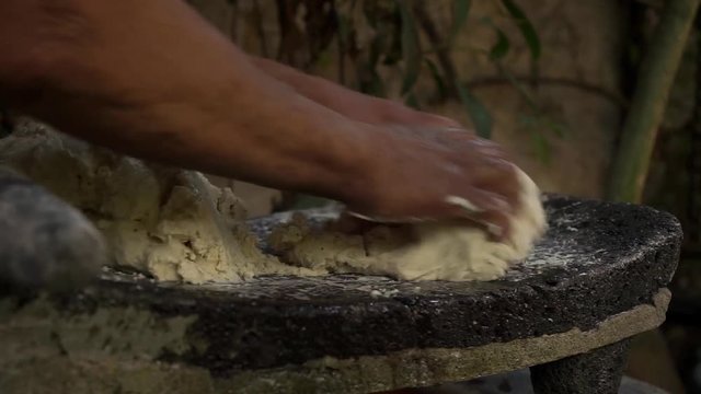 Mexican woman from Cuetzalan making authentic tortilla dough in a typical stone “metate”