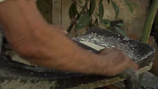 Mexican woman from Cuetzalan making authentic tortilla dough in a typical stone &ldquo;metate&rdquo;