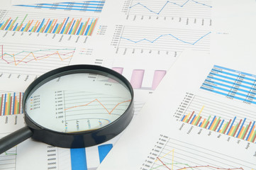Business concept, magnifying glass on financial charts and graphs