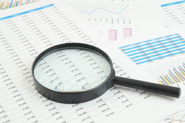 Business concept, magnifying glass on financial charts and graphs