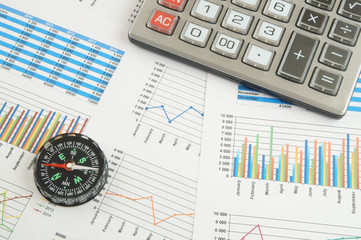 Navigation in financial world concept, calculator and compass on financial charts and graphs