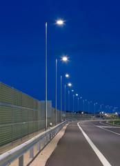 evening empty road with modern LED street light and noise barrier