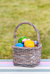 Colorful Easter eggs in wicker basket. Seasonal spring decoration.