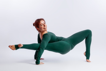 Obraz premium woman in sports overalls doing yoga, standing in an asana balancing pose - posture connection on white isolated background. The concept of sports and meditation. Training for stretching and yoga