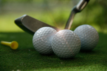 Golf ball and golf club in beautiful golf course at Thailand. Collection of golf equipment resting on green grass with green background
