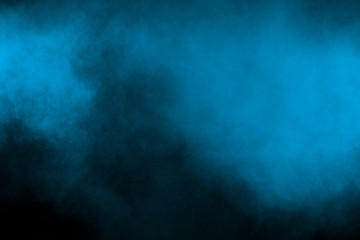 Throwing blue powder out of hand against black background. Stopping the movement of blue holi on the air use for abstract background.