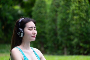 Pretty girl listening music with her headphones in outdoor. Nature and recreation.