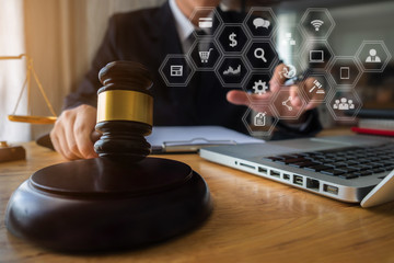 justice and law concept.Male judge in a courtroom the gavel, working with digital tablet computer on wood table.