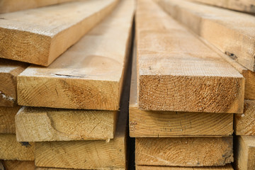 Stacked lumber. Folded wood.Closeup wooden boards.The surface of the end of the board.Lots of planks stacked on top of each other in the warehouse.Lumber for use in construction.