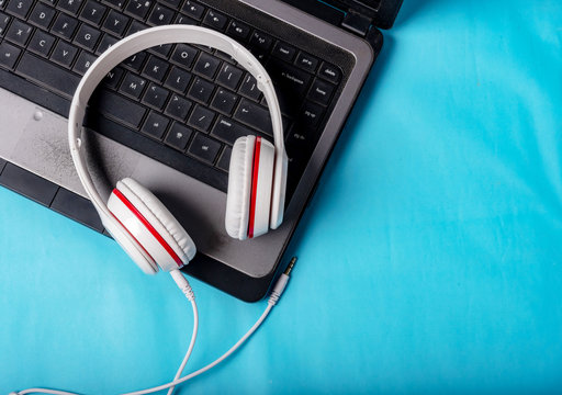 White Red Music Headphones On Technology Background Notbook Computer On A Blue Background. Happy Holidays.