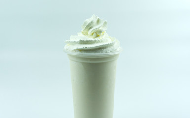 Whipping cream on Fresh milk drink in a cool glass on white background, food concept front view.