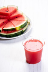Healthy watermelon drink and fresh sliced watermelon on white wooden background