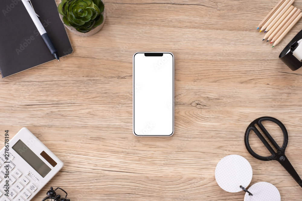 Poster mobile mock up on office desk table top view with stationery,notebook,plant on wooden table background.smart phone screen for display of design.business object flat lay.clipping path device template.