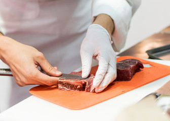 Chef cutting fresh raw meat with knife in the kitchen, Chef cutting beef on a board