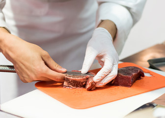 Chef cutting fresh raw meat with knife in the kitchen, Chef cutting beef on a board