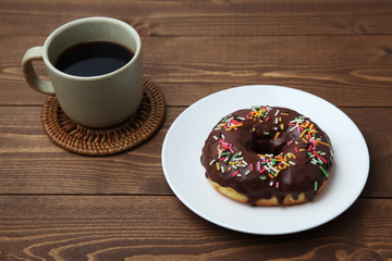 お皿にのせた チョコレート ドーナッツ とホットコーヒー 木のテーブル
