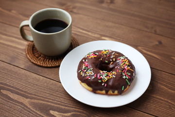お皿にのせた チョコレート ドーナッツ とホットコーヒー 木のテーブル