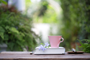 Pink coffee cup with small purple flower  and notebook
