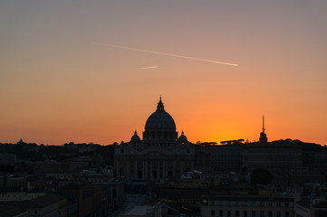 Fototapeta na wymiar Dark silhouette of the St Peters Basilica against bright red sunset sky