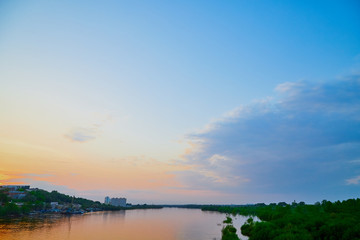 Landscape with sunset, clouds, river and city in the distance summer evening