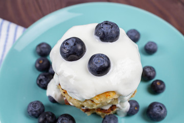 pile of homemade pancakes with blueberries and sour cream sauce. Homemade cheese pancakes