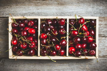 Ripe and juicy cherries in wooden crate on the dark rustic background. Selective focus. Shallow...