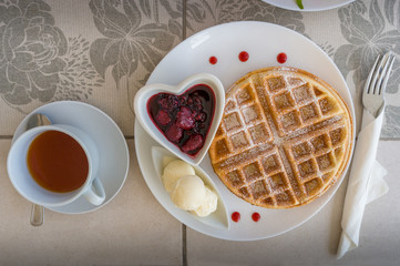 Top view of table setting with belgian waffles, ice cream and jam with tea